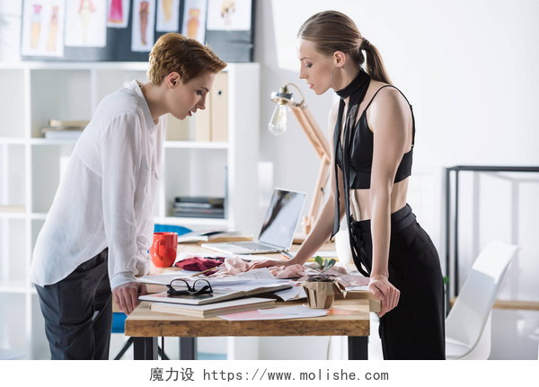 两个时尚设计师在讨论问题时尚的年轻时装设计师在办公室一起工作
